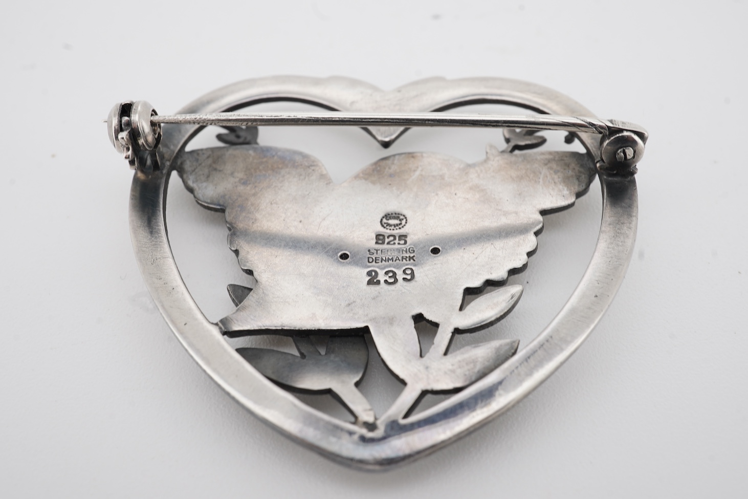 A Georg Jensen sterling heart shaped brooch, designed by Arno Malinowski, depicting a robin with frond, design no. 239, width 40mm.